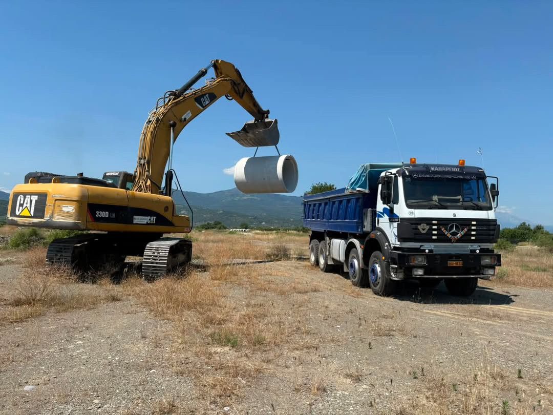 Χωματουργικές εργασίες Εκσκαφέας CAT ανυψώνει σωλήνα δίπλα σε φορτηγό Kathargios